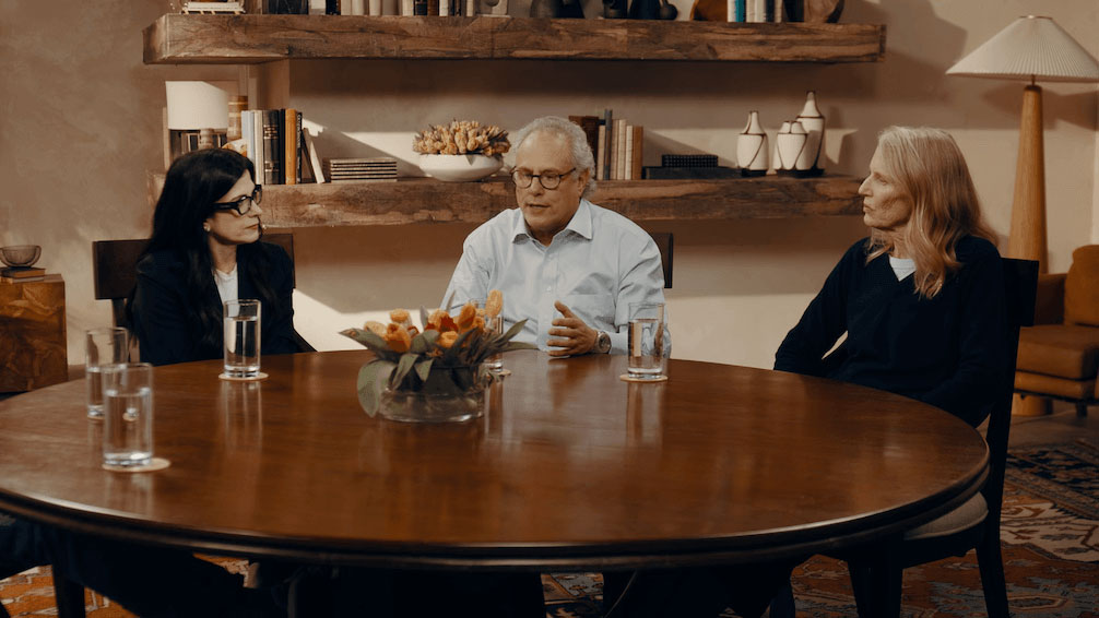 Video play button with image of a doctor and care partner listening to someone talk about living with Parkinson’s-related hallucinations and delusions